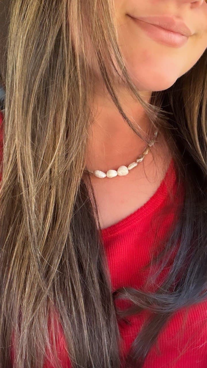A dainty shell-bead necklace worn with a red top